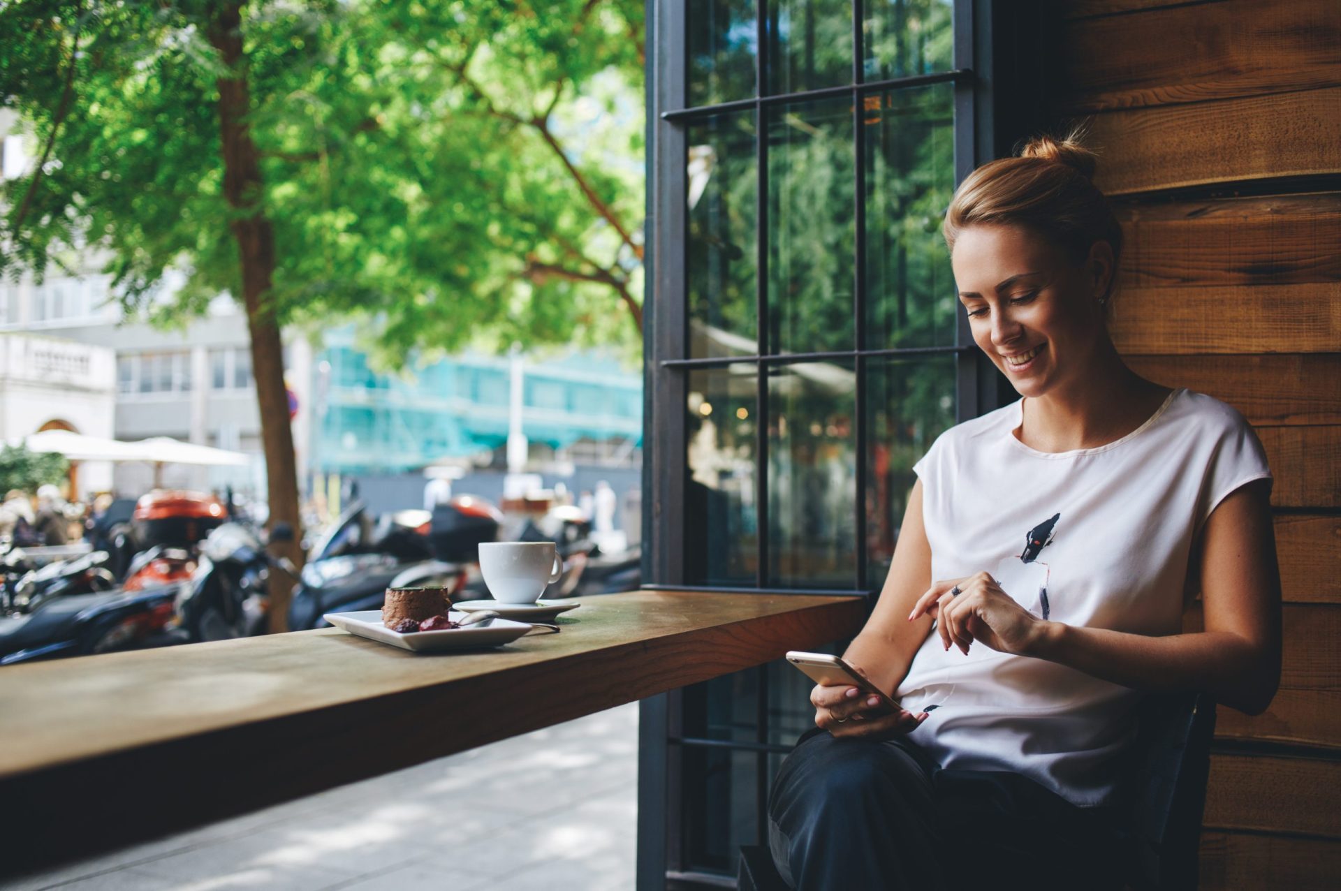 Mujer tomando un café en un bar mientras mira el móvil